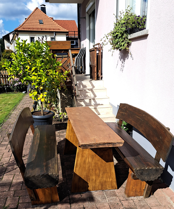 Im Außenbereich steht eine gemütliche Sitzgelegenheit aus Holz.